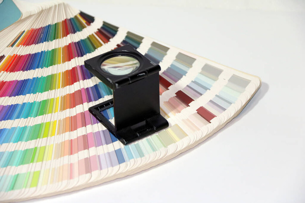 Verre grossissant carré noir et catalogue de palettes d'échantillons de couleurs arc-en-ciel, livre d'échantillons de couleur isolé sur fond blanc.  - Photo, image
