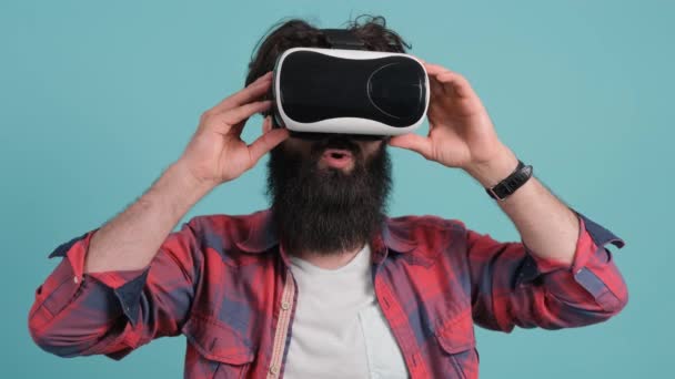 Bärtiger Mann mit Virtual-Reality-Brille. Studioaufnahme, türkisfarbener Hintergrund. - Filmmaterial, Video