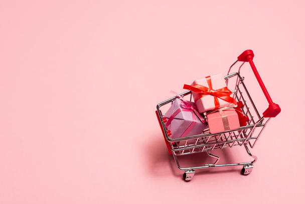 vista de ángulo alto del carrito de compras de juguetes con regalos en rosa, concepto de viernes negro  - Foto, Imagen