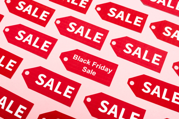 bovenaanzicht van rode etiketten met verkoop en zwarte vrijdag belettering op roze - Foto, afbeelding