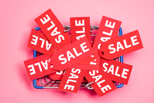 top view of tags with sale lettering in shopping basket on pink, black friday concept  - Photo, Image