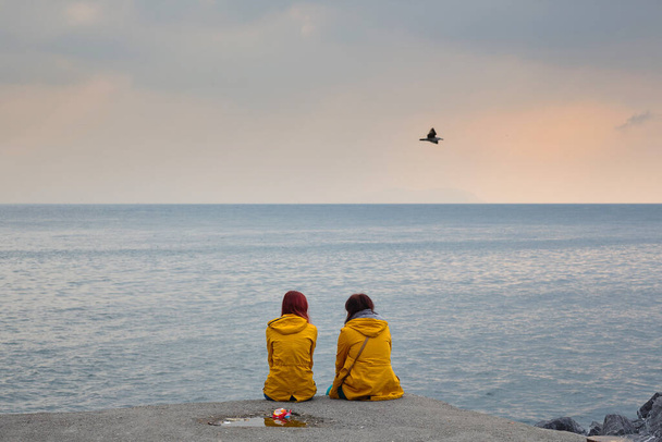 Dos chicas con chaquetas amarillas en la orilla del mar y una gaviota. Estambul - Foto, imagen