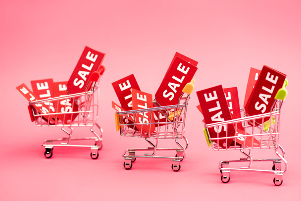 red tags with sale lettering in shopping carts on pink  - Photo, Image