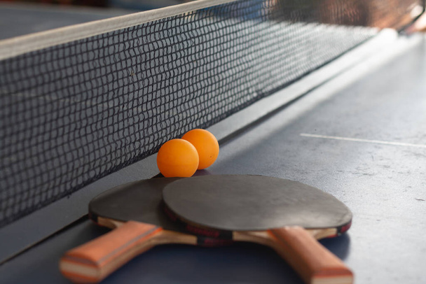 Zamknij pomarańczową piłkę z rakietką do tenisa stołowego na czarnym stole. - Zdjęcie, obraz