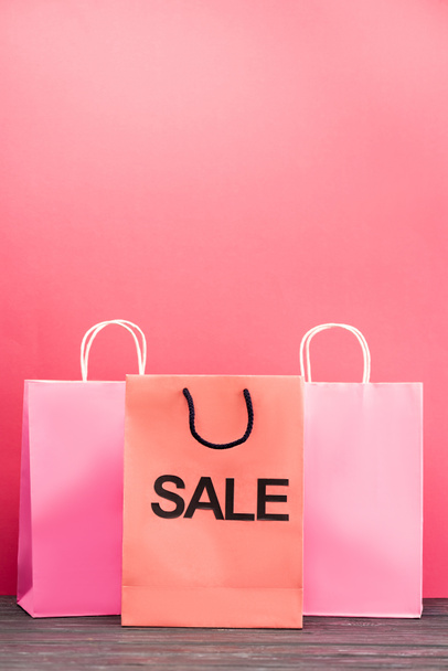 shopping bag with sale lettering near paper packets on pink, black friday concept  - Foto, imagen