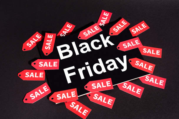 placard with black friday lettering near sale tags on dark background  - Foto, Imagen