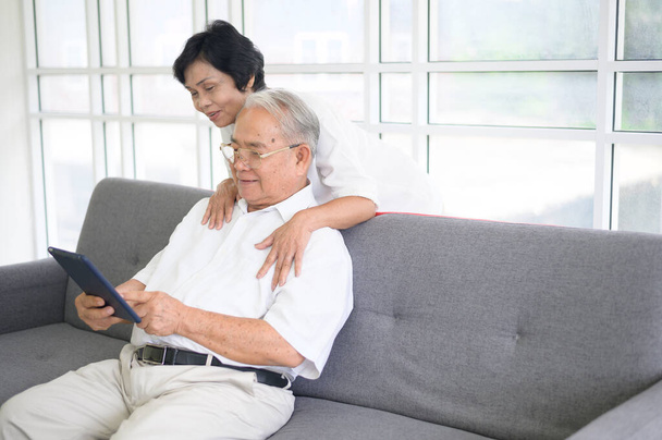 A happy senior Asian couple is using tablet and talking with family on webcam at home, retirement concept. - Foto, immagini