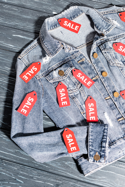 vista superior de etiquetas vermelhas da venda na jaqueta azul da ganga, conceito preto da sexta-feira  - Foto, Imagem
