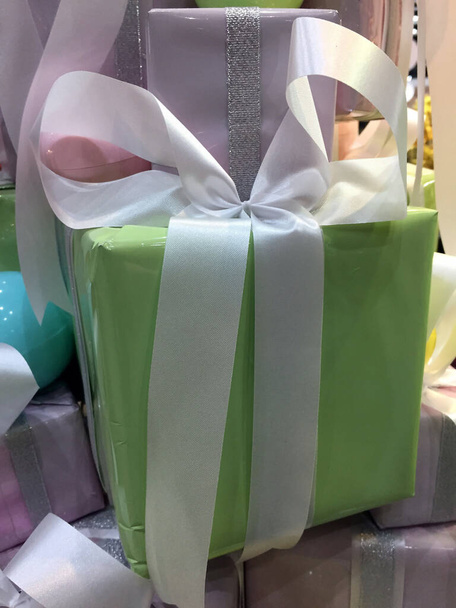 Christmas gift, Soft green gift box with white ribbons in the middle of soft purple gift boxes. - Photo, Image