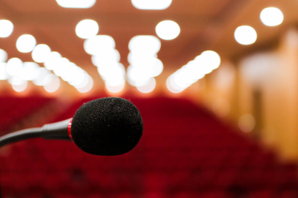 close up photo of a microphone with blurred background and bokeh lights of audiitorium with selective focus on microphone.Stage mic fear concept image - Photo, Image