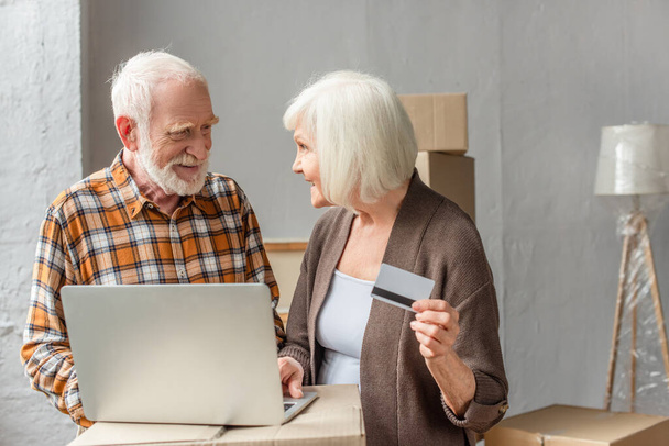 усміхнена старша пара робить покупку онлайн за допомогою ноутбука та кредитної картки
 - Фото, зображення
