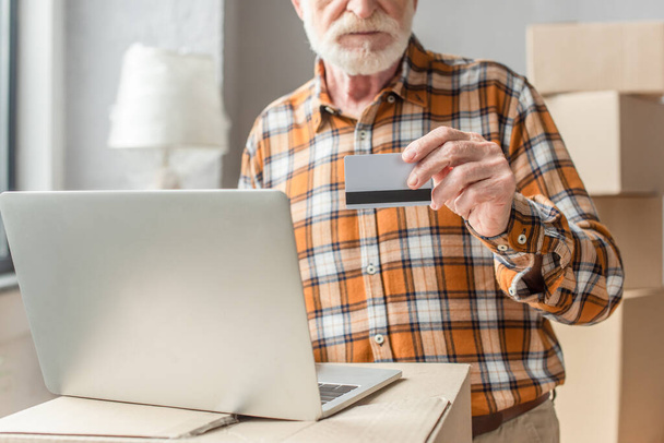 częściowy widok seniora dokonującego zakupów online kartą kredytową i laptopem - Zdjęcie, obraz