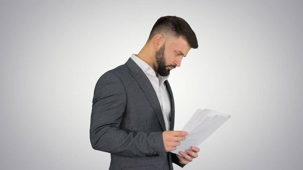 Turk businessman standing and looking at documents on gradient b - Фото, зображення