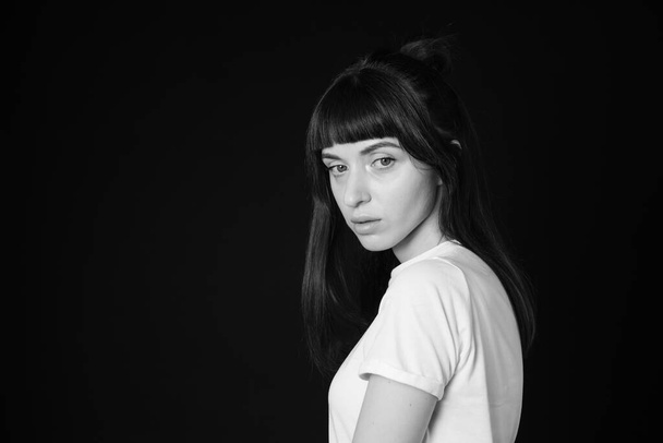 Sideview studio portrét krásné brunetky v bílém prázdném tričku, na prostém černém pozadí, oči zavřené - Fotografie, Obrázek