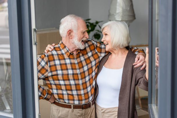 laughing senior couple looking and embracing each other in new house - Fotoğraf, Görsel