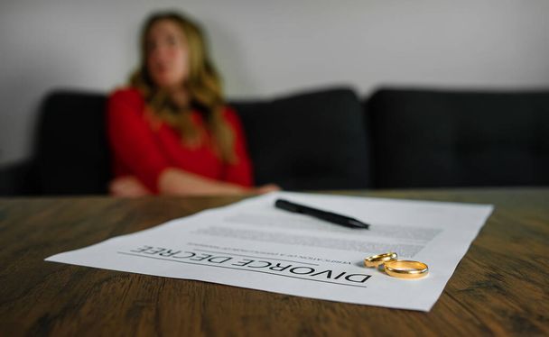 Divorce decree document. Woman is upset on the background. - Photo, image
