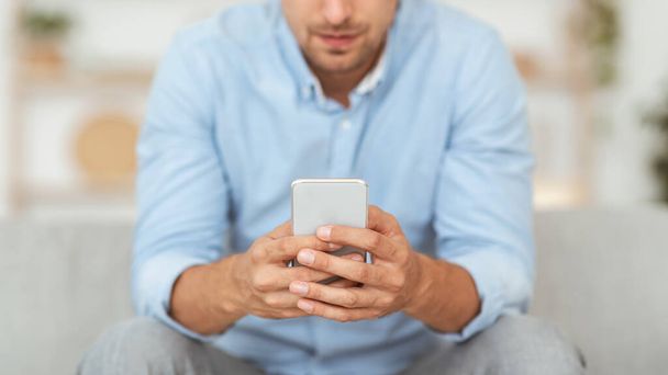 Closeup of adult guy using smartphone at home - Foto, Imagen