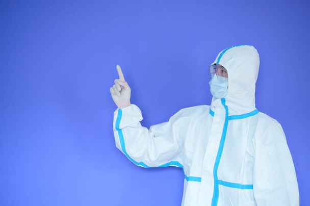 An Asian man is wearing ppe suit on purple background . - Photo, Image