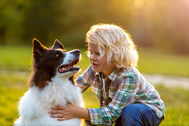 Little boy playing with his dog outdoors in the park - Foto, Imagen