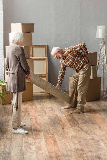 longitud completa del hombre mayor que sufre de dolor de espalda, mientras que la alfombra rodante con la esposa - Foto, Imagen