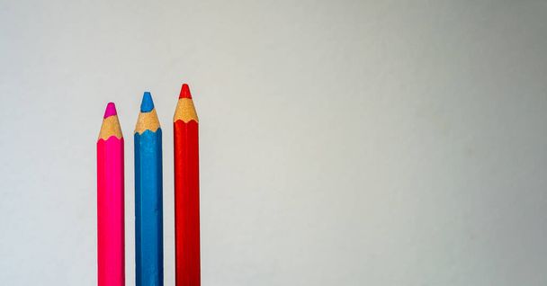 Beyaz arkaplanda izole edilmiş pembe, mavi ve kırmızı kalemler, metin için minimalist arkaplan. - Fotoğraf, Görsel