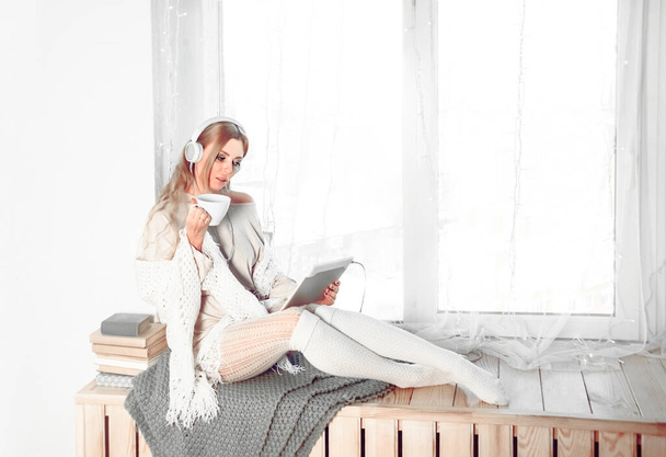 woman sitting on window sill and reading e-book.  - Fotografie, Obrázek