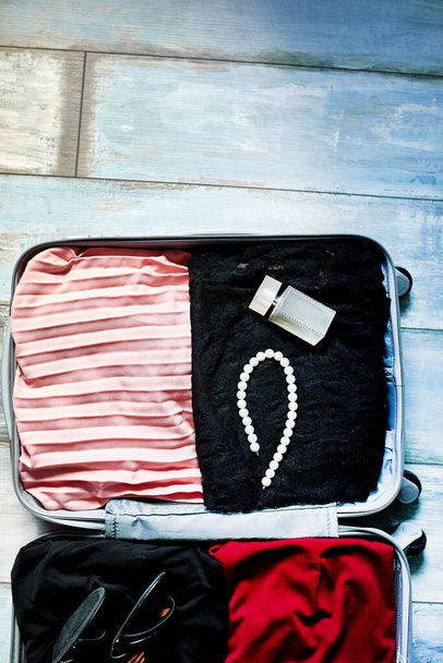 Pakowanie walizki w domu z kobiecych przedmiotów, akcesoria w walizce na podróż, podróż, wakacje. Przestrzeń kopiowania. - Zdjęcie, obraz