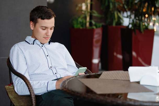 Man met smartphone aan tafel in een café. - Foto, afbeelding