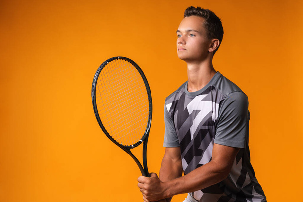 Portrait of a young man tennis player on orange background - Fotó, kép