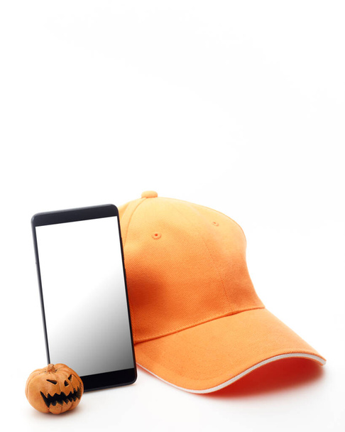 Szczęśliwego Halloween Pumpkin jack o latarni ze smartfonem pusty i pomarańczowy kapelusz. Zakupy online koncepcja dostawy - Zdjęcie, obraz