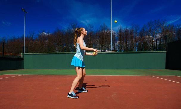 Sahada tenis raketi tutan beyaz elbiseli ve topuklu ayakkabılı seksi kız tenisçi. Genç kadın tenis oynuyor. - Fotoğraf, Görsel