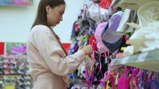 žena nakupující si vybírá dětské plavky v obchodě - Záběry, video