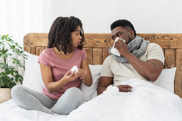 Enfermo afroamericano envuelto en pañuelo sentado en la cama - Foto, Imagen