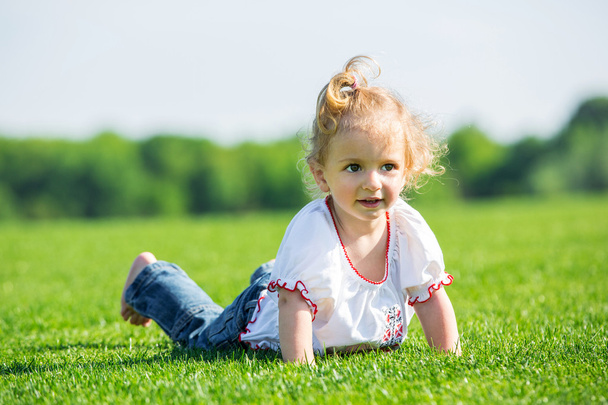 Pequena menina feliz em uma grama
 - Foto, Imagem
