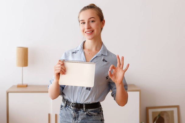 Girl holds white sheet and shows sign at home - Valokuva, kuva