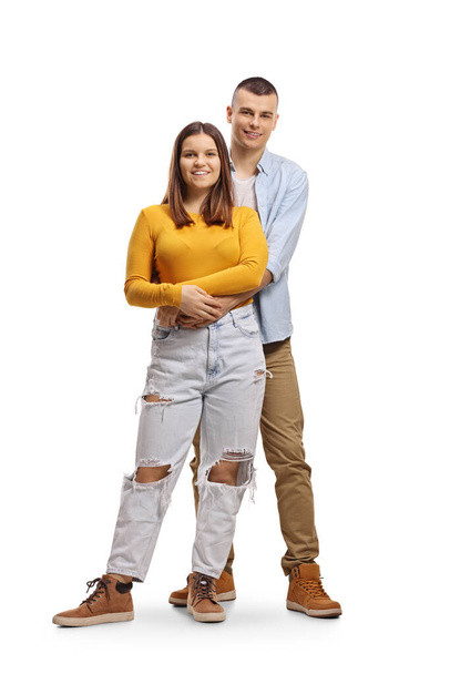 Full length portrait of a young man embraceing a young woman from behind isolated on white background - Photo, Image