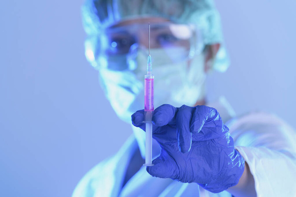 Laboratuvarda çalışan bilim adamı elinde yeni bir anti-viral ilaçla bir şırınga tutuyor. - Fotoğraf, Görsel