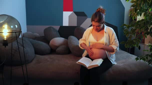 A terhes nő csupasz hassal hangosan olvassa a könyvet, és becsukja. - Felvétel, videó