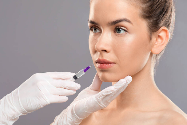 Cosmeticista irreconhecível em luvas injetando preenchimento labial para bela senhora - Foto, Imagem