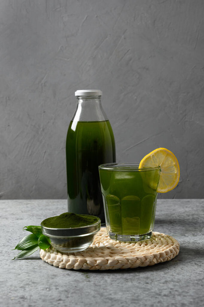 Chlorella healthy Detox beverage with lemon in glass on a grey background. Close up. Vertical format. - Fotoğraf, Görsel
