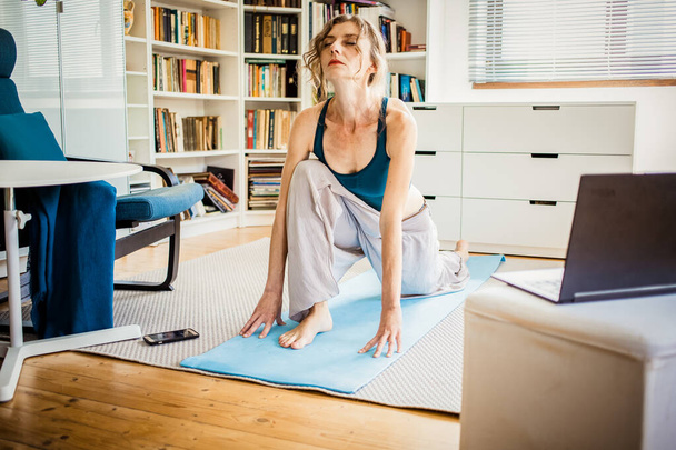nő csinál jóga asanas otthon laptop - Fotó, kép
