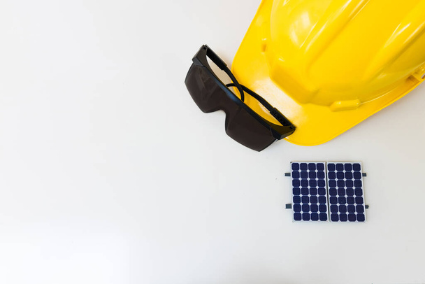 Imagen del concepto de energía de células solares. Panel solar, casco de seguridad y herramientas de trabajo aisladas en blanco, vista superior - Foto, imagen