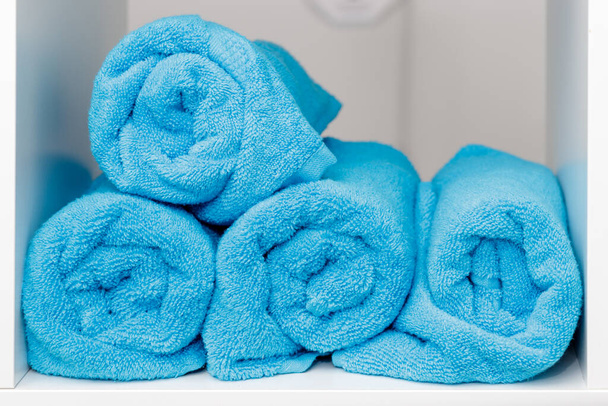 Una pila de toallas suaves azules en el estante blanco en el salón de spa - Foto, imagen