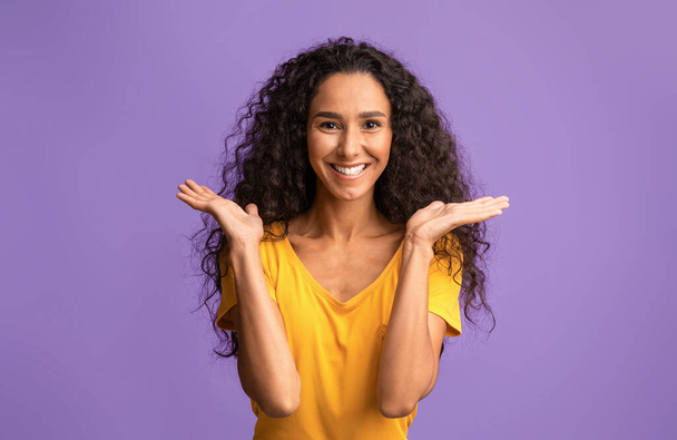 Nadšené radostné brunetky skákání se zvednutýma rukama přes fialové pozadí - Fotografie, Obrázek