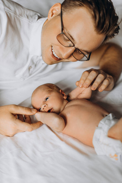 Loving father with adorable newborn baby girl, caring dad hold tiny arms of little daughter, enjoy tender parenting moments, smiling, fatherhood concept - Photo, Image