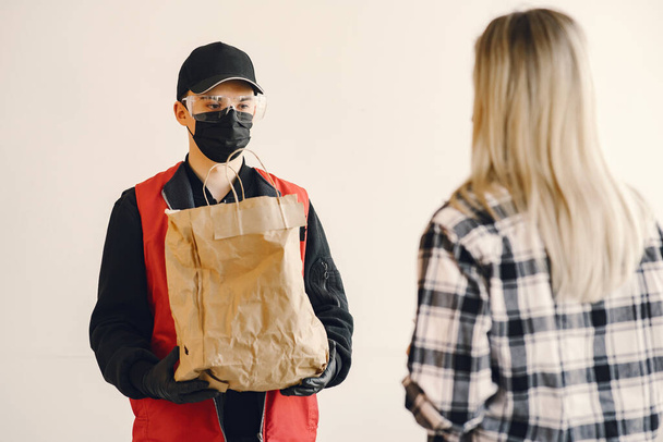 Delivery man in a medic mask with woman - Foto, imagen
