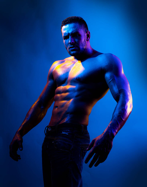 Topless shirtless male model. Naked bodybuilder on Blue neon light. - 写真・画像