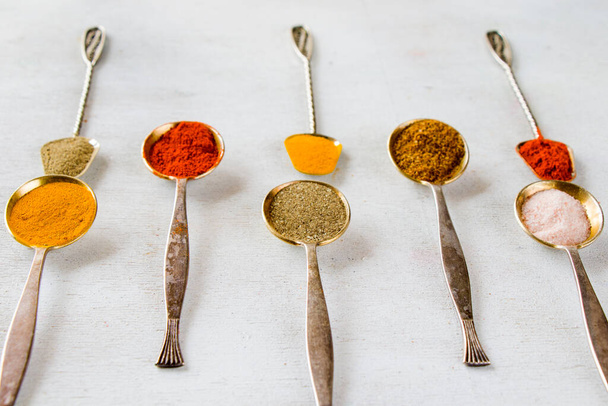 variation of spices on the vintage silver spoons, all spices on the table, colorful food background - Photo, image