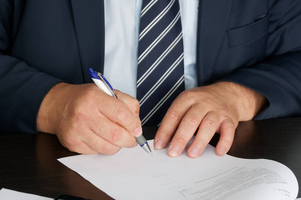 A manager, civil servant or lawyer in a dark suit signs a document. Conducting correspondence. Close-up. Shallow depth of field. No face  - Photo, Image