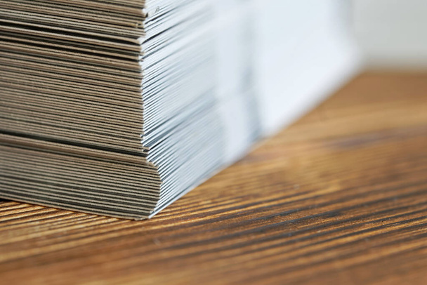 Na dřevěném povrchu je naskládáno mnoho listů bílého papíru nebo lepenky. Katalog nebo kartotéka v kancelářské práci nebo účetnictví. Makro. Mělká hloubka pole                                - Fotografie, Obrázek